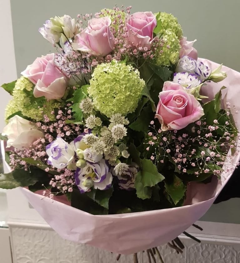Pink and white flower bouquet with roses, hydrangeas, and babys breath wrapped in pink paper